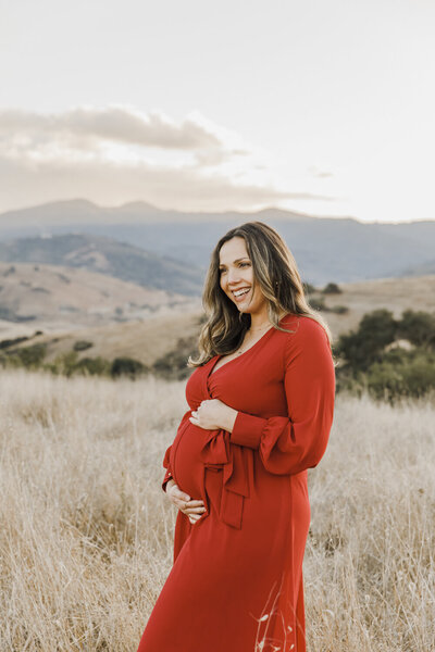 Pregnant woman in red dress in a field in California