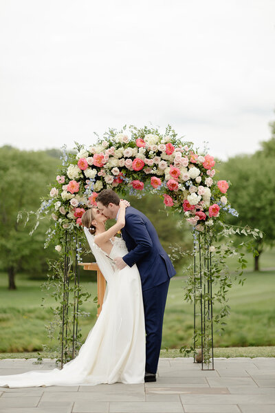 Bride and groom kissing in front of their wedding arch