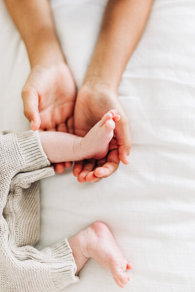 older brother holding newborn baby feet during a session in home in St Pete