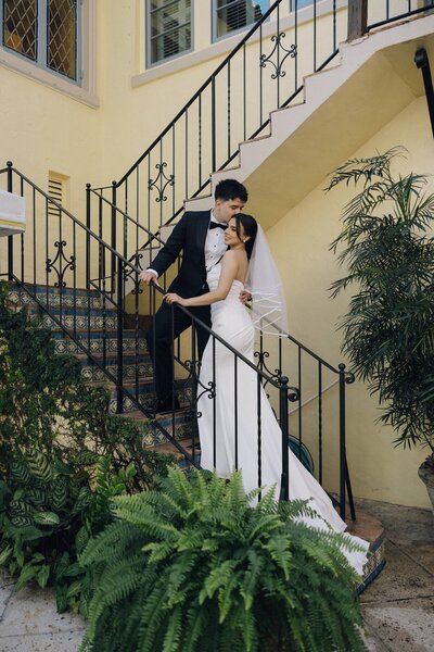 groom kisses brides forehead on staircase