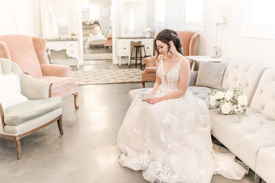 Bride sitting in a pale pink room, reading a heartfelt letter from her future husband, savoring the emotions and anticipation before their wedding ceremony.