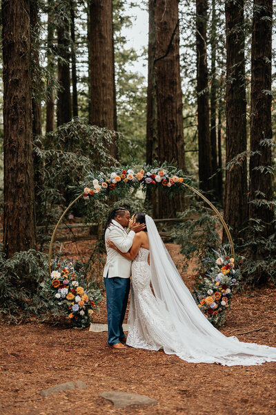 bride and groom kissing with wedding party cheering