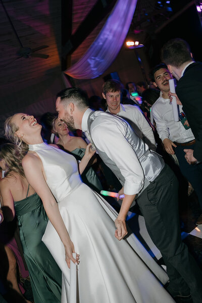 Bride and groom dancing at their wedding reception, laughing and having the time of their lives.