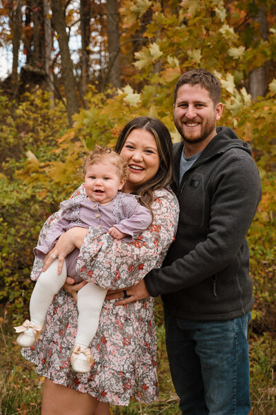 Mom and dad with baby daughter in Michigan fall colors