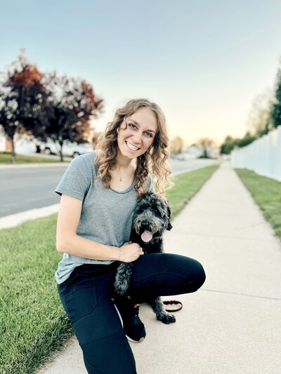 Amazing Dog Trainer kneeling next to her dog on the sidewalk