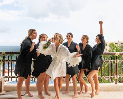 Bridesmaids celebrating in black robes before a luxury wedding at a Texas Hill Country venue, captured by CMH Studios.