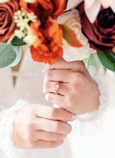 Close-up of a bride's hands holding a bouquet with a rose gold engagement ring.