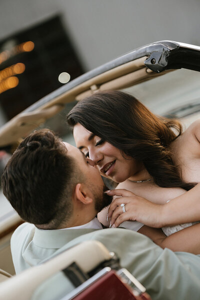 Bride and groom kissing in their vintage classic jaguar