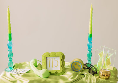 Styled desktop flat lay with green candle, eyeglasses, and framed 715 print — brand photo for Studio Seven Fifteen