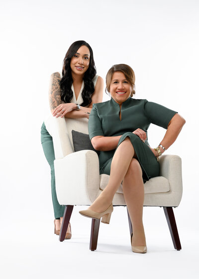 Two poised businesswoman in blazers and heels standing arms folded in luxury sugar house home radiating confidence and sophistication.
