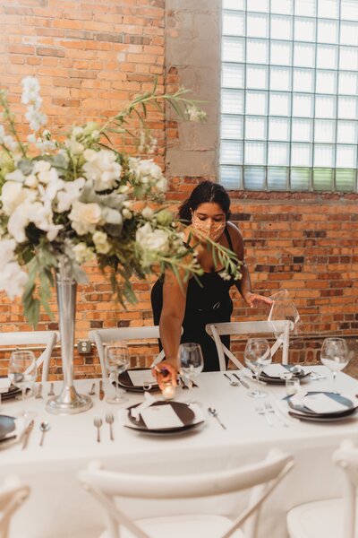 Wedding planner places candles on a table at Outreach Event Space in Kansas City