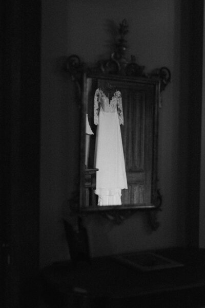 Elegant black and white film-style wedding photograph of the bride’s dress hanging up while she gets ready for her Richmond, VA wedding.