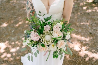 Soft pastel bridal bouquet with blush and cream roses, accented with dusty miller, designed by Leigh Florist for an elegant wedding.