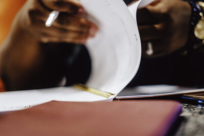 Hands flipping through the pages of a physical planner, preparing for the next client project. A moment of organization and strategy in action.