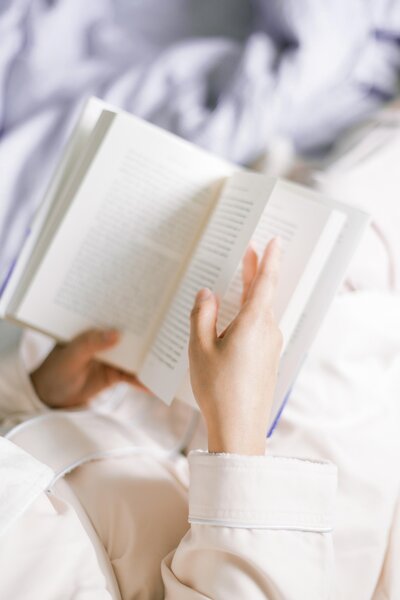 Leyendo un libro sobre la cama.