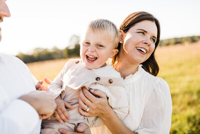 Mother holding and laughing with her child in a field