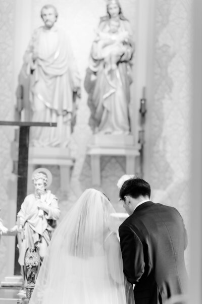 bride and groom praying during a Catholic wedding ceremony