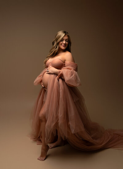 Strapless peach tulle maternity gown with dramatic off-shoulder sleeves and flowing train