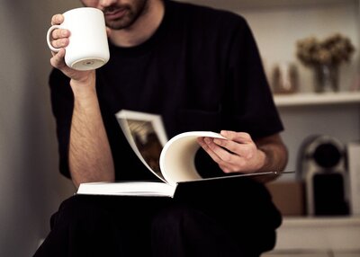 Man Sitting and Reading while Drinking Coffee