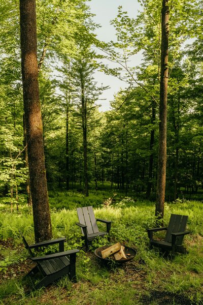 Three chairs outside a cozy home with breathtaking vieews of mountains and pine trees.