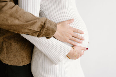 Close-up of baby bump with parents' hands during Indianapolis maternity photos