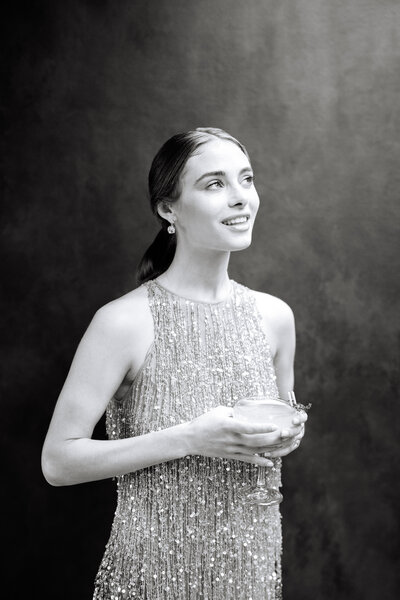 black and white photo of woman in beaded dress holding drink