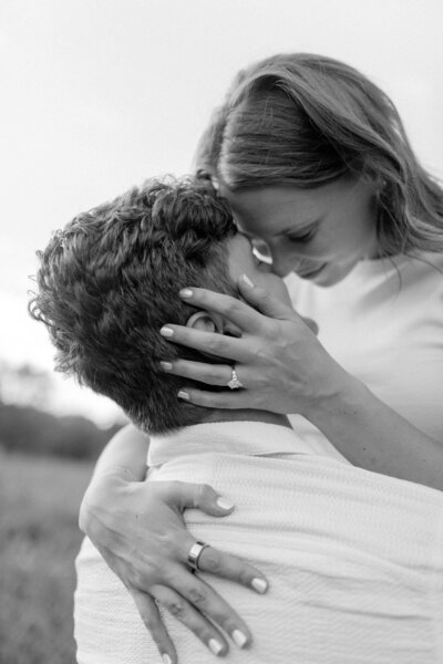 a woman holding a man's face as they touch foreheads