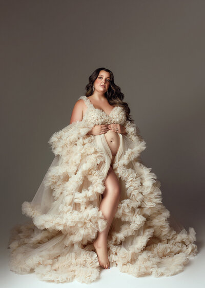 Glowing expectant mother in flowing gown during an studio maternity session near Oswego, NY.
