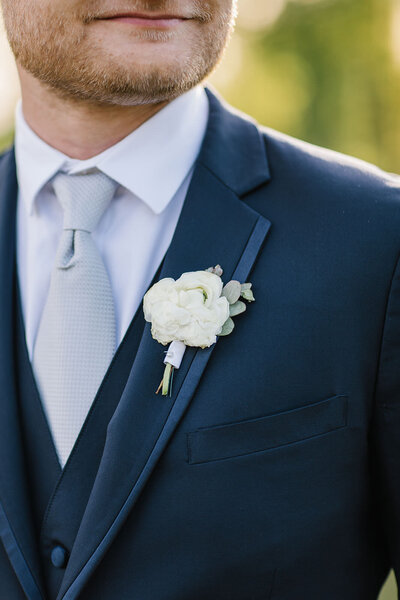 Detail close up photo of boutonniere and classy blue tux