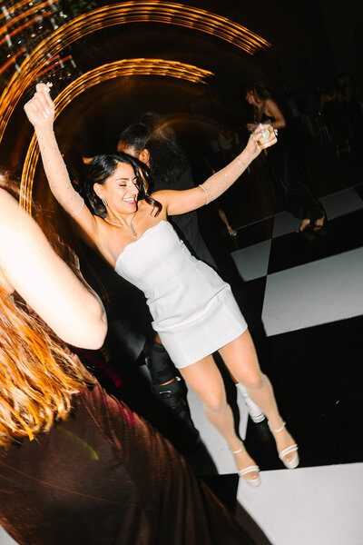 Flash photo of bride dancing in a short white dress