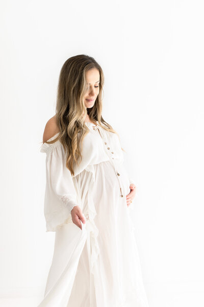 Pregnant mother gazing down at belly dreamily during pregnancy photoshoot