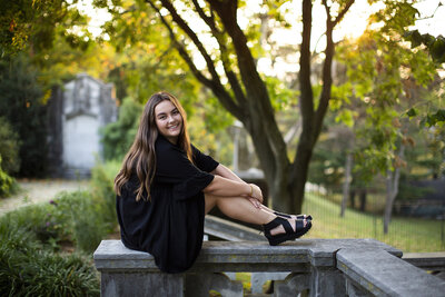 Highschool senior girl sits on stone wall in Shadyside for her sneior portraits.