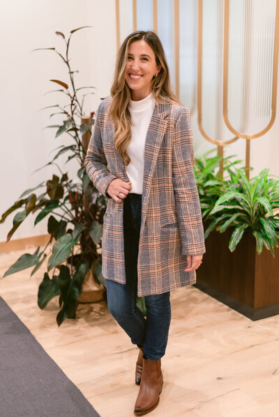 Trauma therapist in Raleigh with brown straight hair posing at the camera with greenery in the background