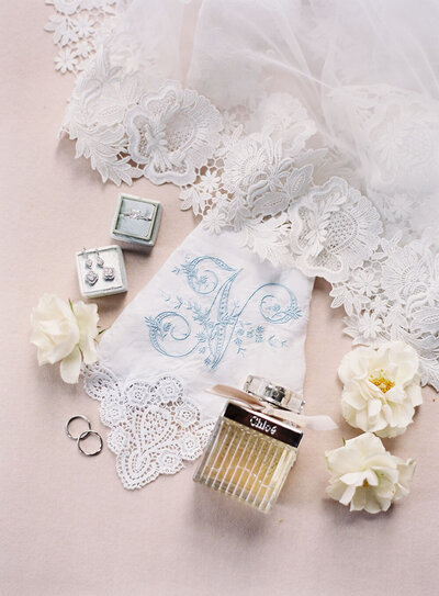 Heirloom handkerchief with lace edging and blue embroidery alongside the bridal veil and Chloe perfume