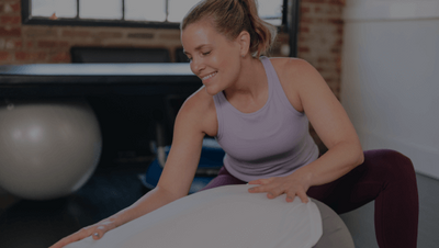 woman assisting a client in a downward facing position on a Pilates reformer 