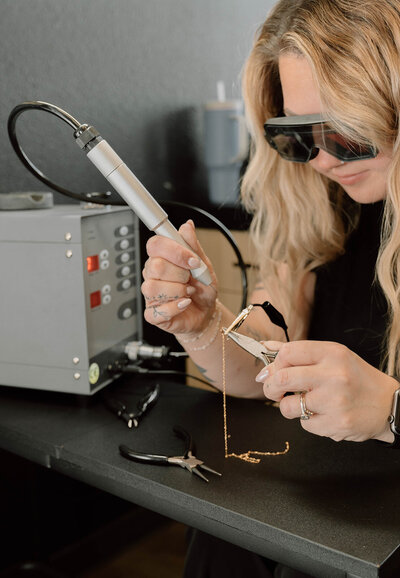 Provider welding custom permanent jewelry bracelet on client at Lavender & Ink Studios