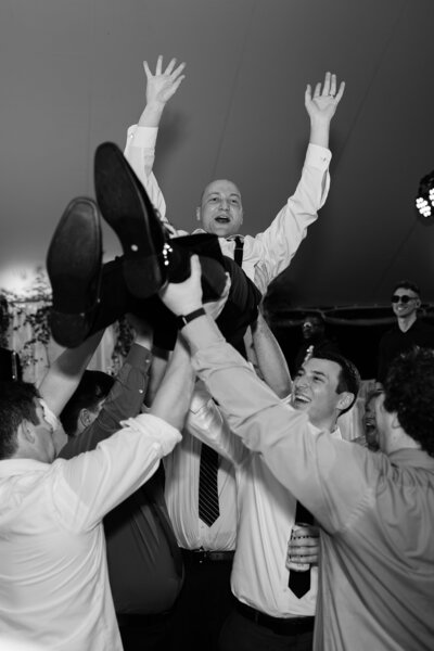 Groom crowdsurfing during wedding reception