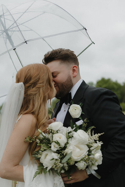 close up photo of bride and groom while they hold a clear umbrella