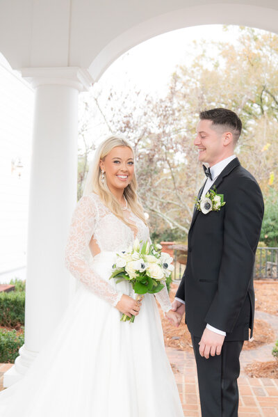 woman in white dress holding flowers standing next to man in black tux