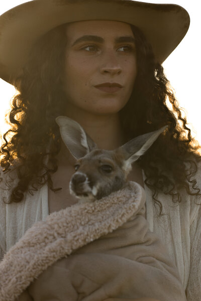 woman in a cowboy hat holding a kangaroo