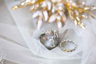 Bride and Grooms promise, diamond engagement, and wedding rings with gold, jeweled hairpiece on veil
