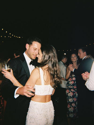 Bride and groom holding hands and walking while bridal party cheers behind them