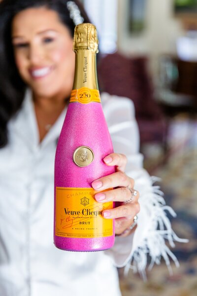 Bride holding pink bottle of champagne