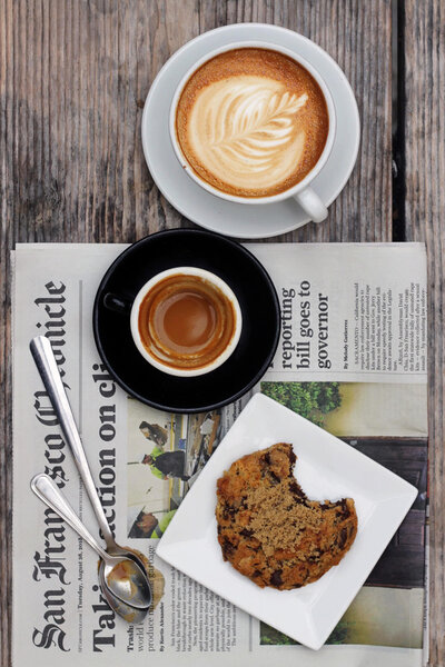 Coffee and cookie plated on top of a San Francisco Chronicle newspaper