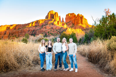 Stacie standing in front of cliffs at sunset with her husband and three kids