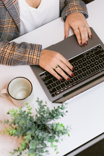 Female with red nail polish typing on a laptop