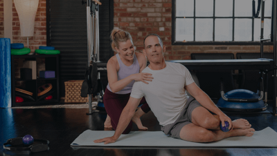 woman helping a man in a pilates class 