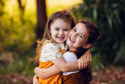 Two little girls hug affectionately in the park, beautifully photographed by Bia Schaefer in Orlando, Florida.