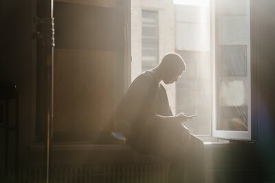 guy sitting in window covered by sun