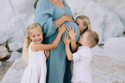 Pregnant mom posing with her three kids